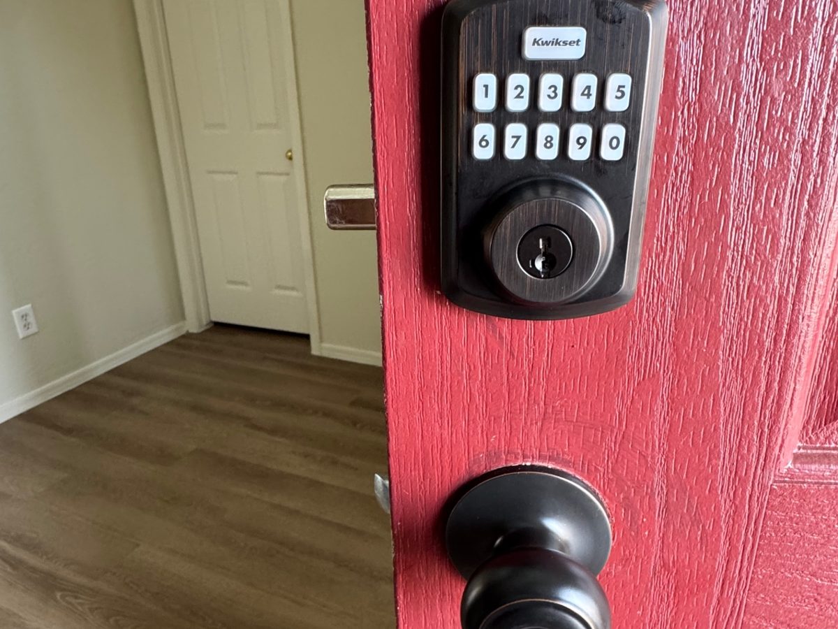 Bronze Kwikset keypad deadbolt and knob on a red front door