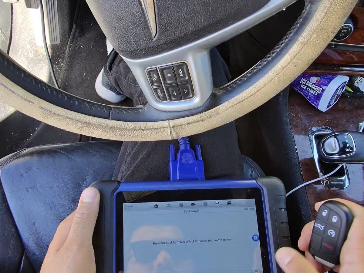Technician programming a key with an Autel diagnostic tablet inside a vehicle