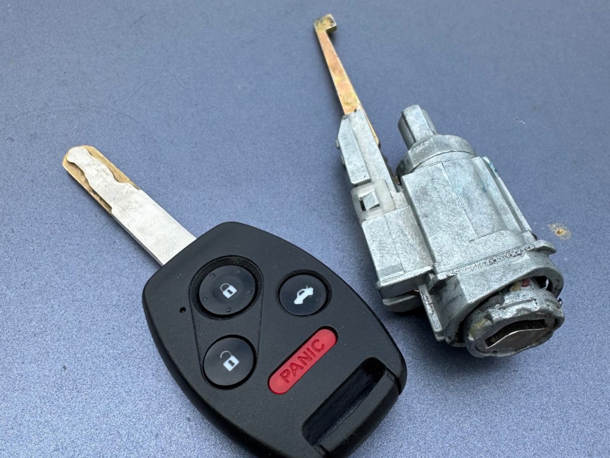 Honda key fob next to a replaced ignition lock cylinder
